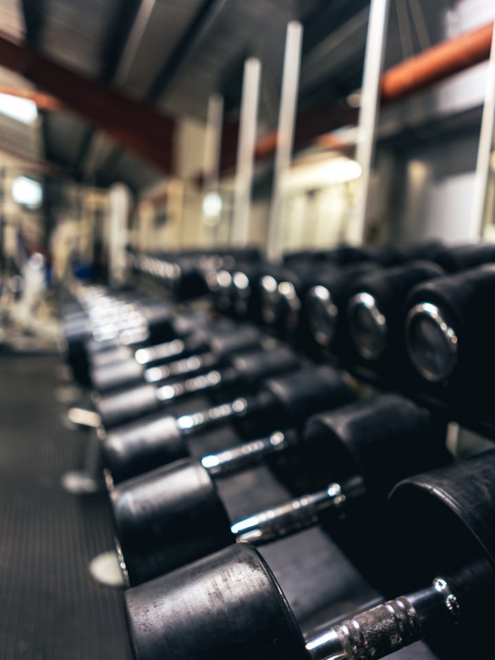 Rij met zwarte dumbbells in een sportschool, vager achtergrond.